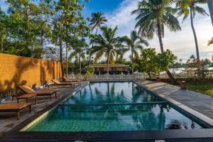 a swimming pool with chairs and palm trees at Kurialacherry House Alleppey in Ambalapulai