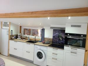 ミルポワにある- - - - -Les Colombages - - - - Chambre d'hôtes-Gîte- Classement Gîte 3 étoilesのキッチン(白いキャビネット、洗濯機、乾燥機付)