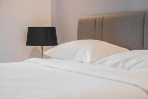 1 cama con almohadas blancas y lámpara negra en 芭提雅Edge极致高端景观房-海景城景巨大顶楼泳池-健身房按摩房乒乓球室花园餐厅, en Pattaya central
