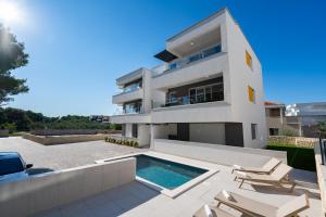 a large white house with a swimming pool at Apartments Break with pool in Novalja