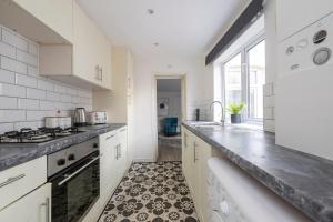 een keuken met witte kasten en een zwart-witte tegelvloer bij Chill in Gill Comfy House, Free Parking x 1 in Gillingham