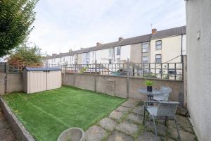 een kleine achtertuin met een gazon en een tafel en stoelen bij Chill in Gill Comfy House, Free Parking x 1 in Gillingham