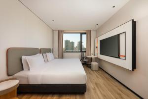 a bedroom with a white bed and a flat screen tv at Holiday Inn Express Shanghai Changyang Road by IHG in Shanghai +69 photos