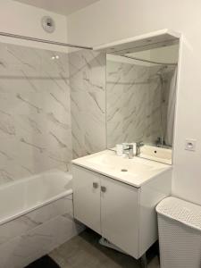 a white bathroom with a sink and a mirror at Appartement cosy proche Disneyland in Serris +5 photos
