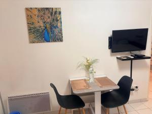ein Zimmer mit einem Tisch und zwei Stühlen und einem Fernseher in der Unterkunft studio proche Orly et villes 91 in La Ville-du-Bois