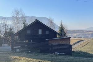 a large wooden house in a field with a fence at 3 Bed Chalet Sleeps 8 -Fireplace & Enclosed Garden in Sohodol