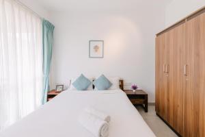 ein Schlafzimmer mit einem großen weißen Bett mit blauen Kissen in der Unterkunft Humble Pineapple by Da Alohas in Calangute