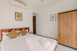 Schlafzimmer mit einem weißen Bett und einem Holzschrank in der Unterkunft Humble Pineapple by Da Alohas in Calangute