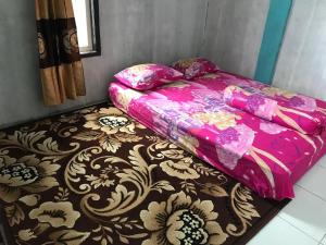 a bed with a pink blanket on top of a carpet at Komodo Wisata Homestay in Komodo