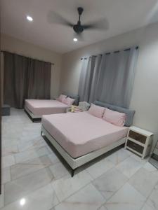 2 bedden in een slaapkamer met een plafondventilator bij Melody Homestay in Kuala Kedah