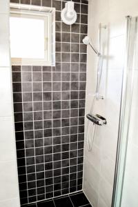 a bathroom with a shower with black and white tiles at First Camp Haganäset - Charlottenberg in Åmotsfors