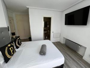 a bedroom with a white bed and a flat screen tv at Puerto Principe PENSIÓN in Santander +68 photos