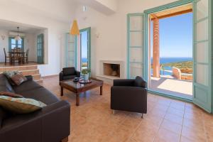 a living room with a couch and chairs and a fireplace at Villa Malia, Eco-Chic, Tranquility, Sea Views & Luxury Cycladic Island Escape in Tálanda