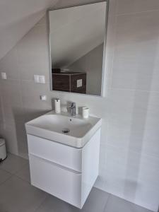une salle de bain blanche avec un lavabo et un miroir dans l'établissement Apartmán By One, à Banská Štiavnica
