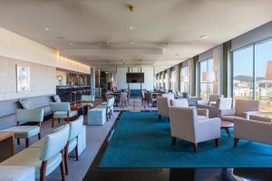 a waiting room with chairs and tables and windows at Hotel de Guimaraes Business & SPA in Guimarães