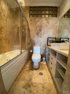 a bathroom with a toilet and a tub and a sink at The Fifth in Luanda +10 photos