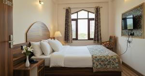 a hotel room with a bed and a window at Hotel Tirupati Inn Hill View in Shimla