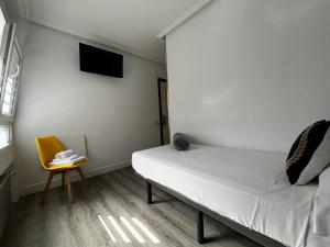 a small room with a bed and a yellow chair at Puerto Principe PENSIÓN in Santander