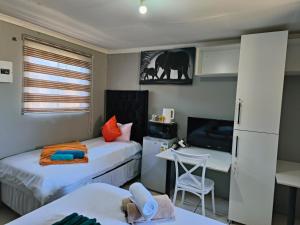 a small bedroom with two beds and a desk at Acama Guest House in Welkom