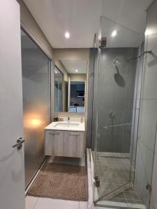 a bathroom with a sink and a glass shower at The Capital Trilogy Hotel in Pretoria