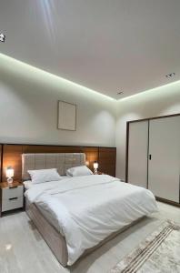 Un dormitorio con una gran cama blanca y dos lámparas. en سويت ضيافة البرج, en Al Kharj
