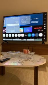 アル・カルジにあるشقق ضيافة البرجの背景に大きなテレビのあるテーブルとテレビ