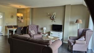 een woonkamer met een bank, stoelen en een tv bij B&B vakantieappartementen Dalerheugte in Dalerveen