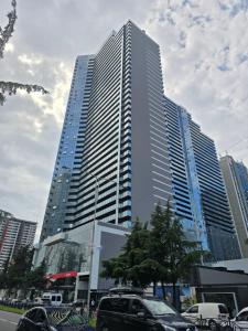 Un edificio alto con coches aparcados delante. en Blue sky, en Itʼkhvisi