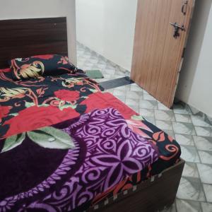 マトゥラーにあるGaurangi Mathura dharamshalaのベッドルーム1室(カラフルな掛け布団付きのベッド1台付)