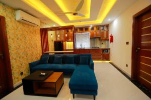 a living room with a blue couch and a kitchen at Qinwan Hotel & Suites in Rawalpindi