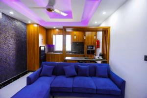 a living room with a blue couch and a kitchen at Qinwan Hotel & Suites in Rawalpindi +8 photos
