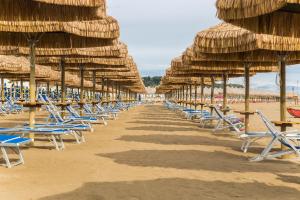 una fila de sombrillas y sillas de paja en una playa en Hotel Mara, en Ortona