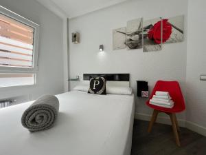 a bedroom with a white bed and a red chair at Puerto Principe PENSIÓN in Santander