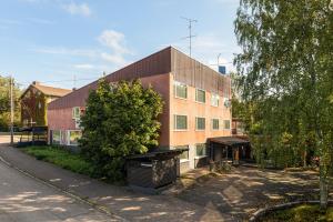 Un edificio de ladrillo con un árbol delante. en Kotimaailma Aparthotel Ankkuri - Two bedroom, en Kotka