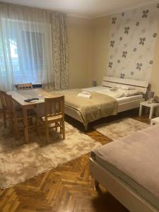 une chambre avec deux lits et une table et des chaises dans l'établissement Csilla Apartman, à Makó