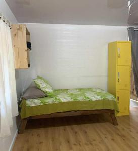 Una cama pequeña con un armario amarillo en una habitación. en Kura Ora Guest House, en Rangiroa