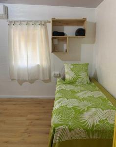 1 dormitorio con 1 cama con edredón verde y ventana en Kura Ora Guest House, en Rangiroa