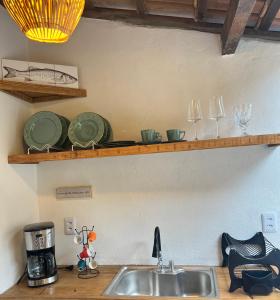 eine Küchentheke mit Spüle und Gläsern auf einem Regal in der Unterkunft chalé coração da vila Caraíva in Porto Seguro + 8 Fotos