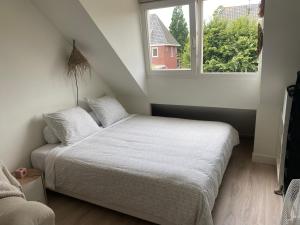 a bedroom with a white bed and a window at Appartement Buissant des Amorie! in Castricum