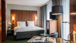 a hotel room with a bed and a table with a book at NH Brussels EU Berlaymont in Brussels