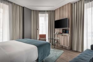 a hotel room with a bed and a flat screen tv at NH Collection Madrid Gran Vía in Madrid