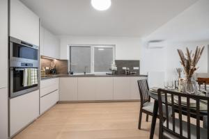 a kitchen with white cabinets and a table with chairs at LAM Cream Old Town Balcony & AC in Bratislava