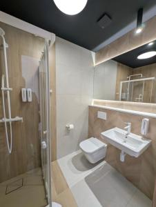 a bathroom with a shower and a toilet and a sink at Hotel Eden in Rzgów