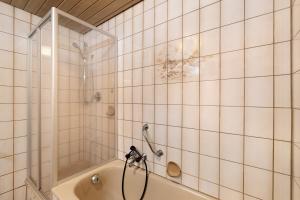 a white tiled bathroom with a shower and a tub at Ferienwohnung Matteit in Bad Peterstal +23 photos