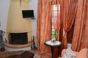 a living room with a fireplace and orange curtains at ΑΡΣΙΝΟΗ apartments1 in Mesochórion +8 photos
