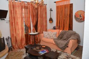 a living room with orange curtains and a couch at ΑΡΣΙΝΟΗ apartments1 in Mesochórion