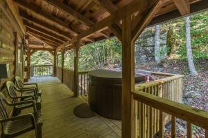 a covered porch of a cabin with a trash can at Hot Tub & WiFi - Big Boulder - Red River Gorge KY in Rogers