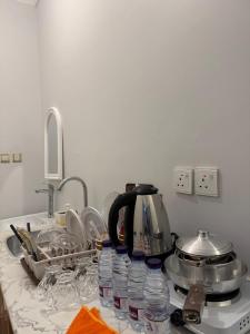 a kitchen counter with dishes and a tea kettle and water bottles at ريحانة الورود للشقق المخدومة -Golden New in Khamis Mushayt