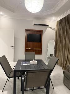 a black dining room table with chairs and a flat screen tv at ريحانة الورود للشقق المخدومة -Golden New in Khamis Mushayt +12 photos