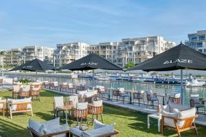 a bunch of chairs and tables with umbrellas next to the water at Marassi Boutique Hotel-Marina 1 in El Alamein
